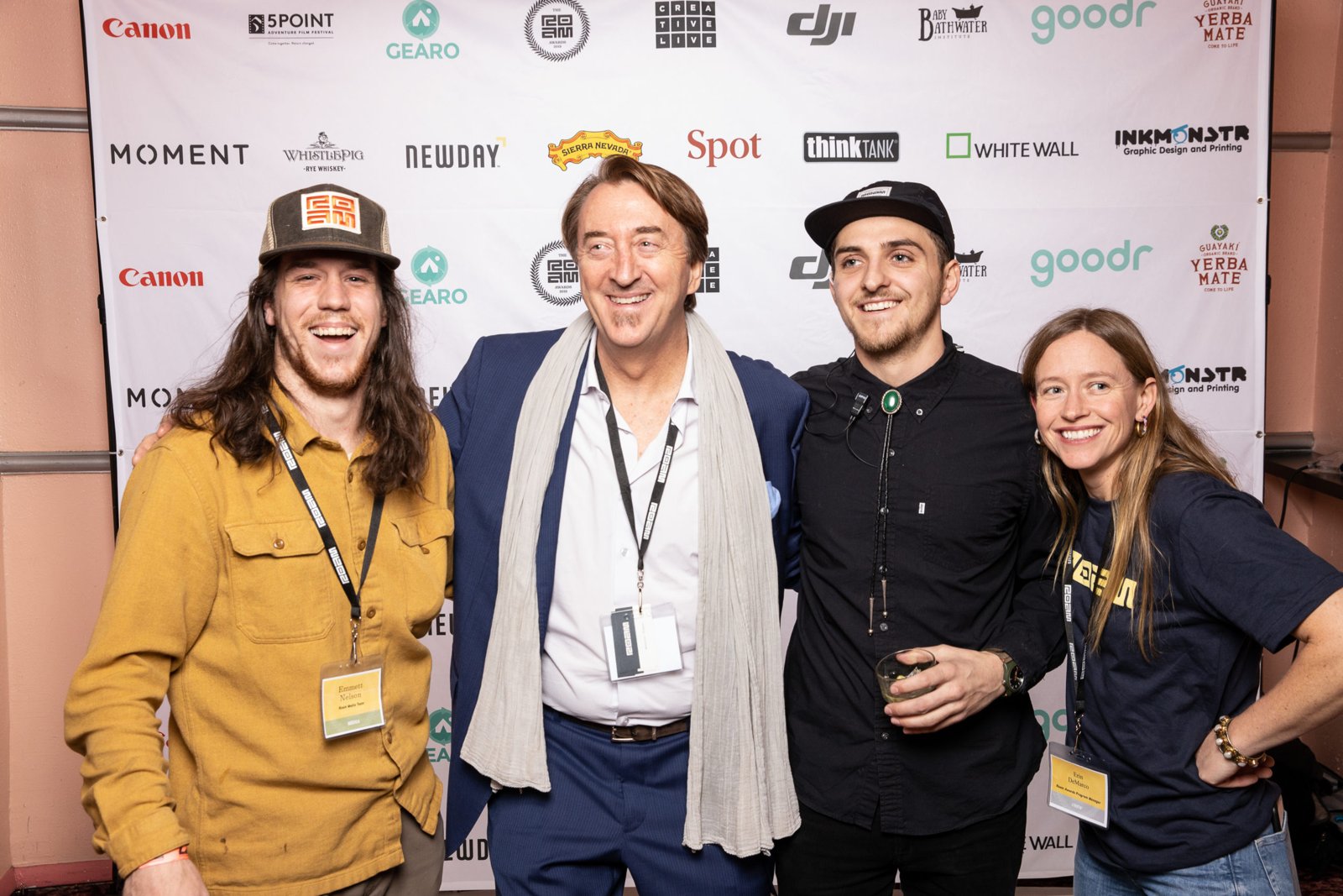 Erin with members of the Roam team in front of the sponsor wall